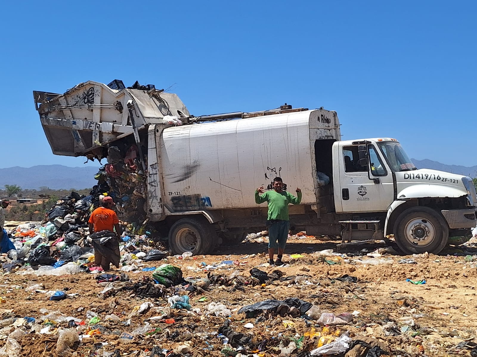 Camión recolector descargando basura en la corona