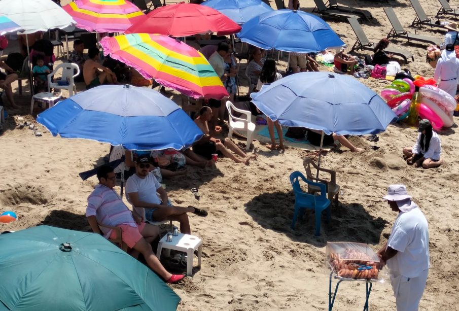 Vacacionistas bajo la sombra de sombrillas instaladas en playas en Semana Santa