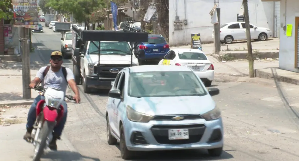 Autos transitando en calle con baches