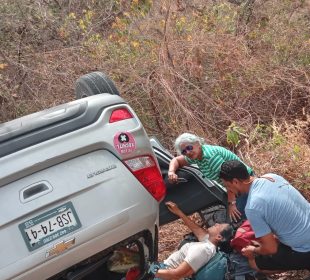 Personas dando primeros auxilios a mujer lesionada por volcadura