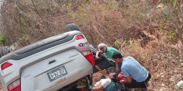 Personas dando primeros auxilios a mujer lesionada por volcadura