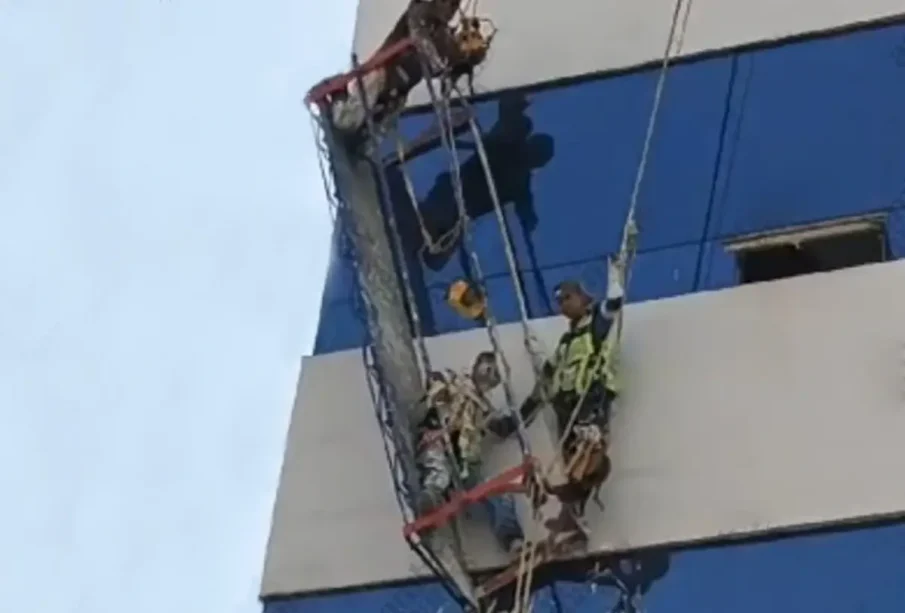 Tres pintores colgando en andamio