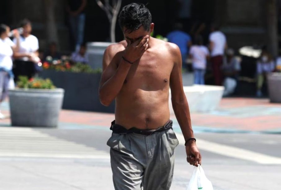 Persona sin playera con calor camina por la calle