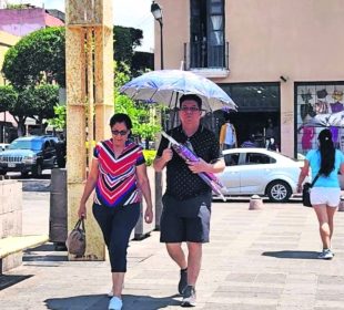 Personas se cubren del calor con un paraguas