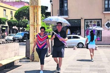 Personas se cubren del calor con un paraguas