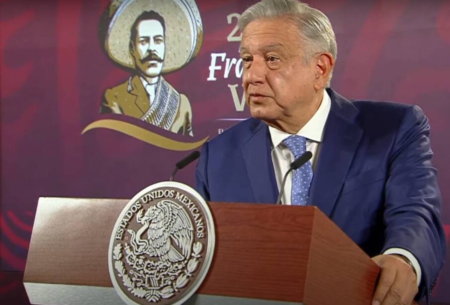 AMLO parado sujetandose del podium