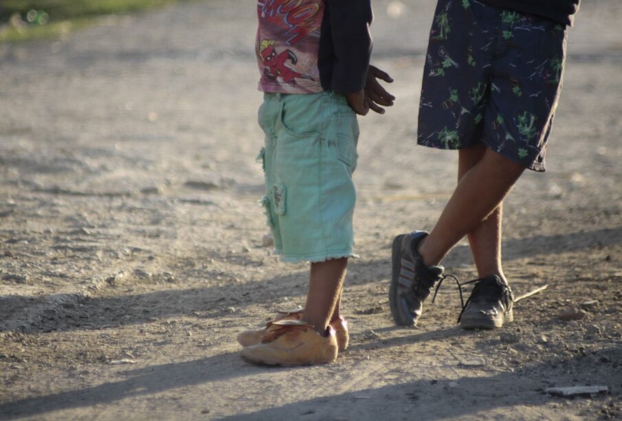 Niños parados en calle de tierra