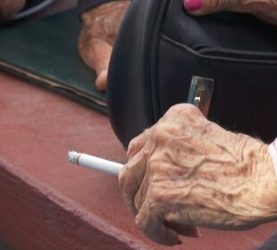 Persona de la tercera edad fumando un cigarro.