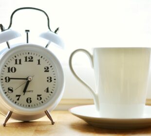 Reloj despertador junto a una taza