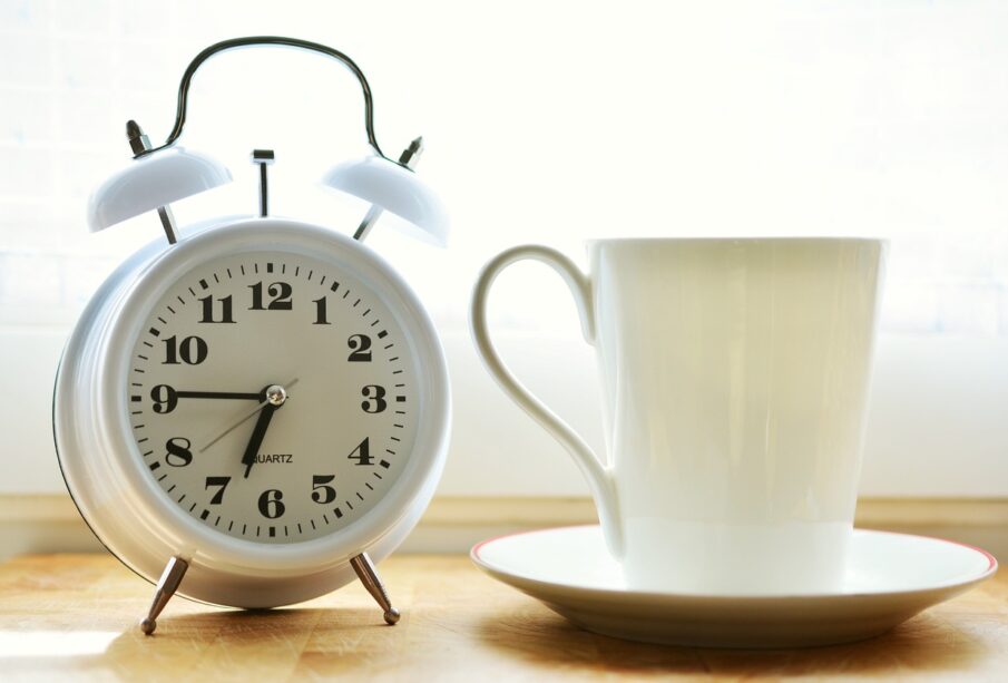 Reloj despertador junto a una taza