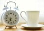 Reloj despertador junto a una taza