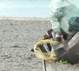 Un bote de basura lleno en una playa