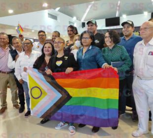 Personas posando con una bandera de la comunidad LGBT+