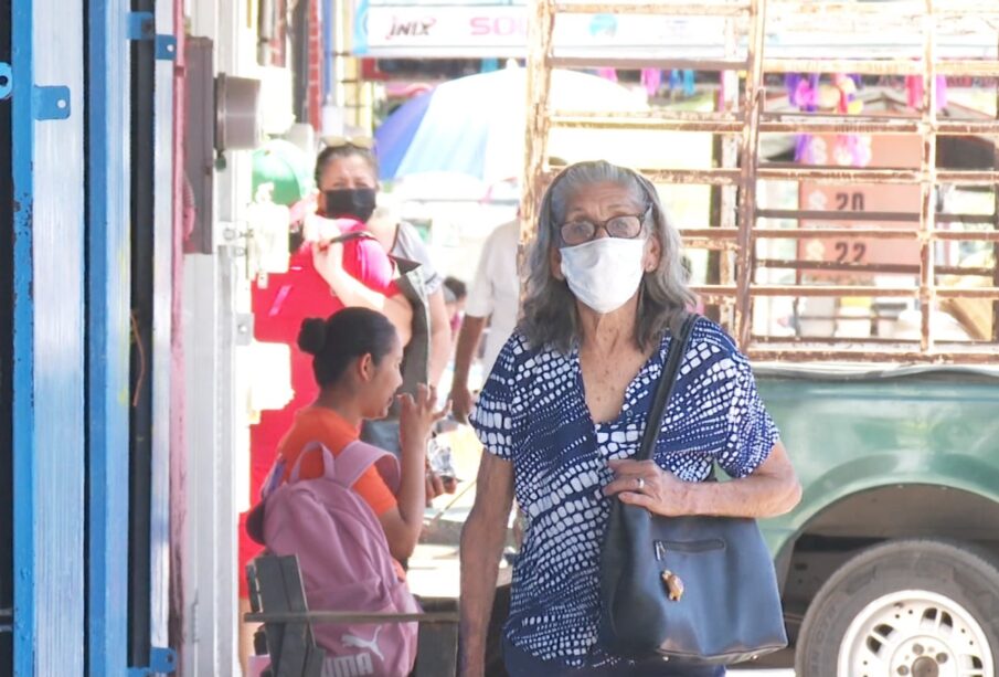 Una adulta mayor caminando con un cubrebocas puesto