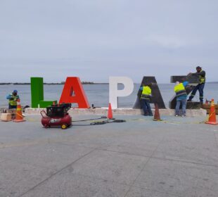 Trabajadores junto a las letras del malecón de La Paz