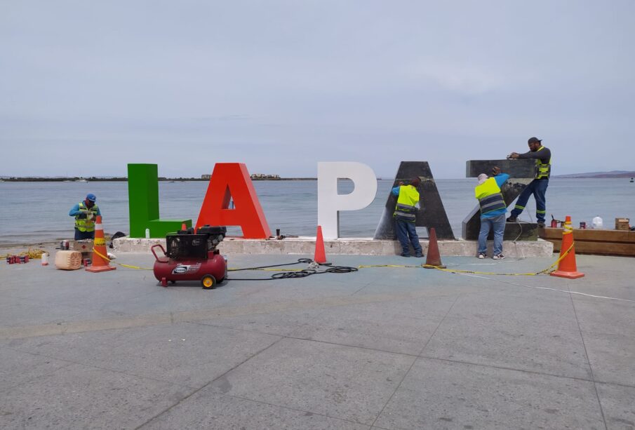 Trabajadores junto a las letras del malecón de La Paz