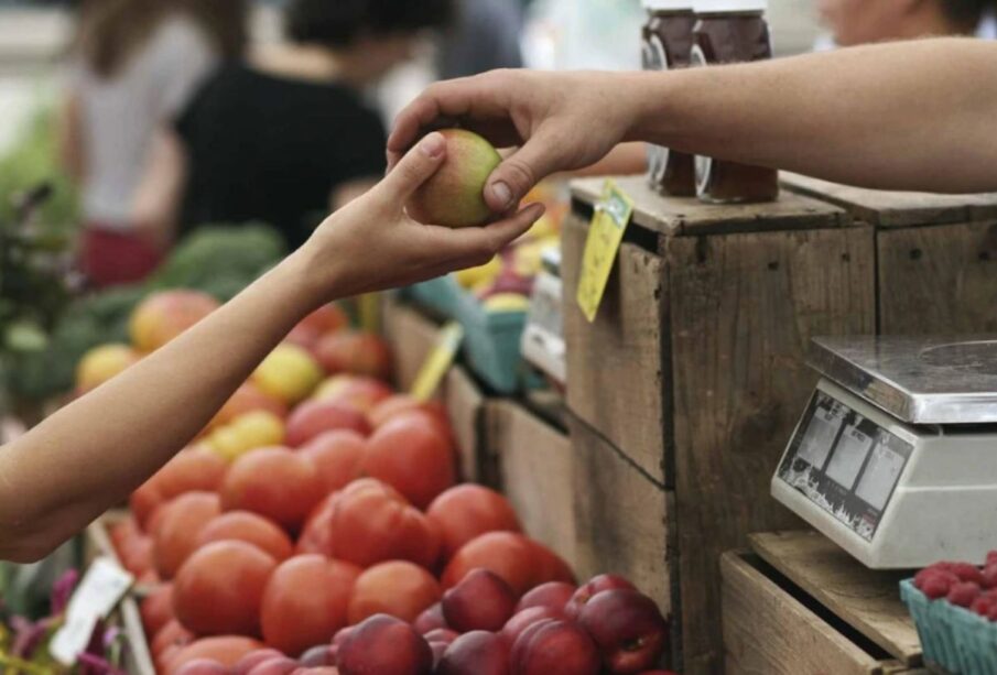 Manos de personas intercambiando una manzana. La inflación ha crecido en Latinoamérica