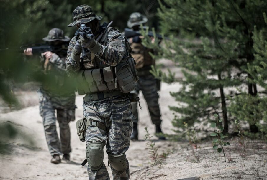 Un militar apuntando con un arma en una práctica de campo