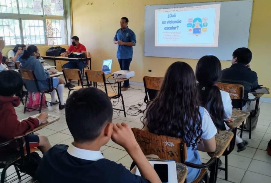 Jóvenes escuchando una plática dentro de un salón de clases