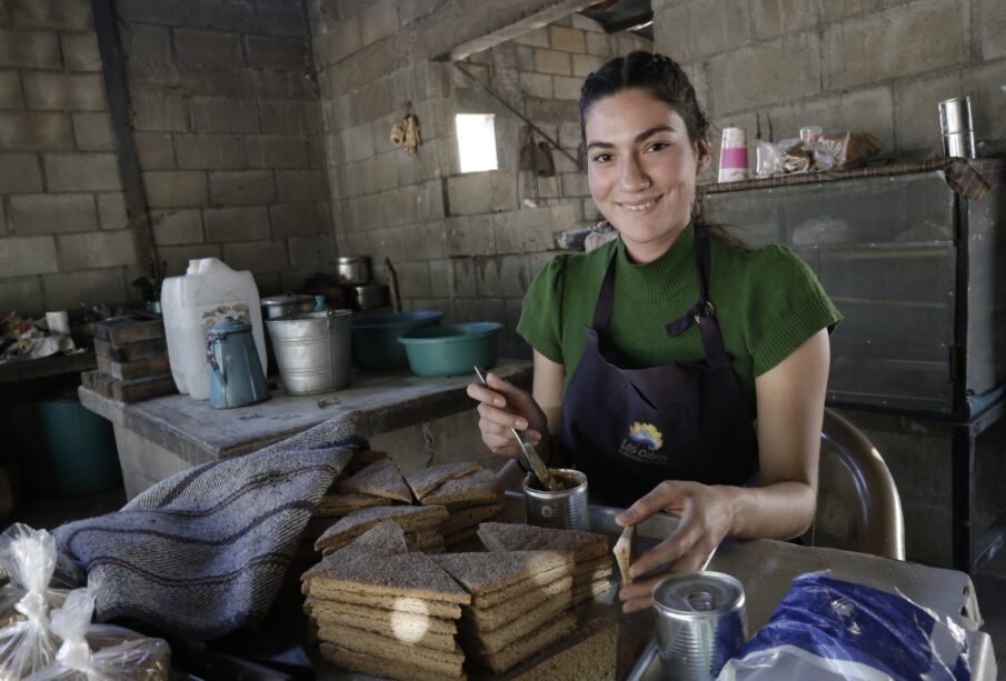 Una mujer frente a una mesa preparando un platillo