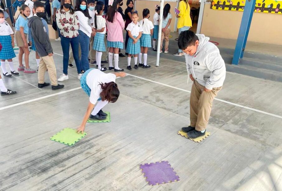 Dos niños jugando con tapetes en un patio escolar