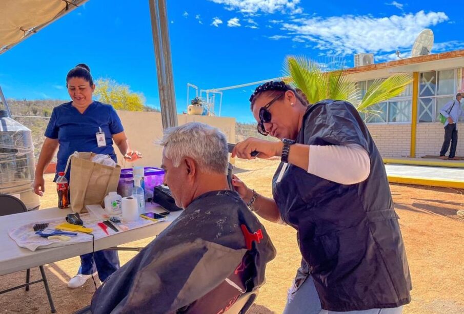 Una mujer cortándole el cabello a un adulto mayor