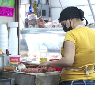 Una mujer manipulando alimentos con un cubrebocas puesto