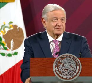 AMLO sonriendo y sujetando podium