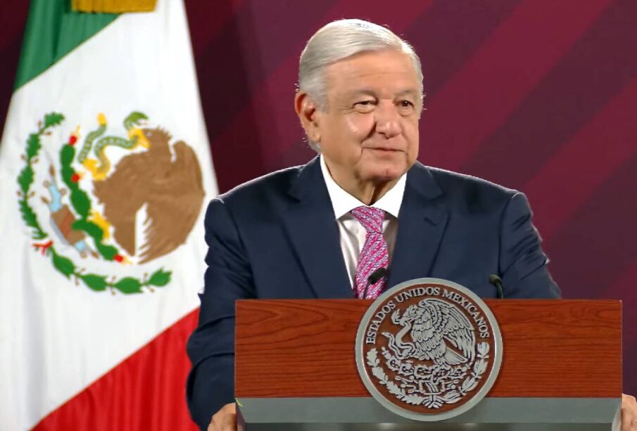 AMLO sonriendo y sujetando podium