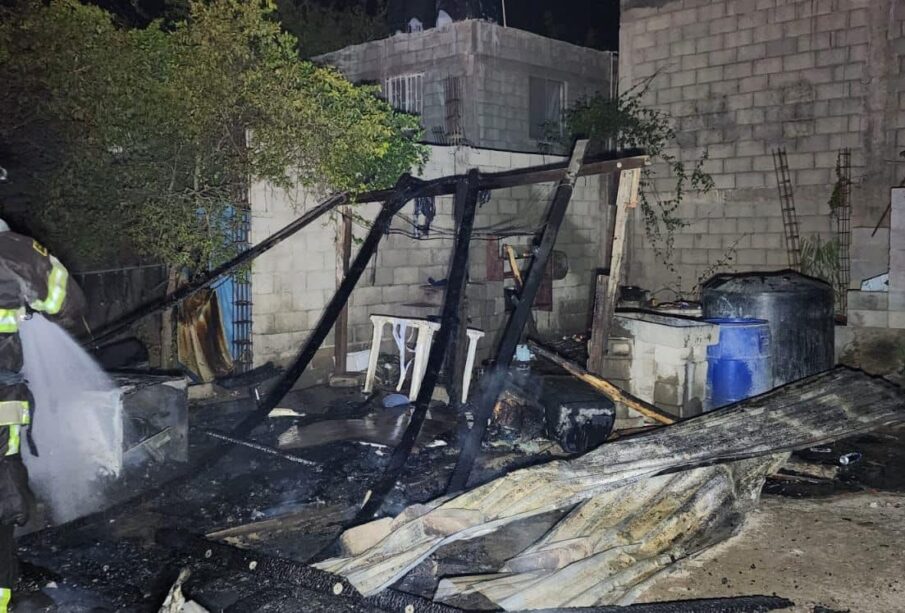 Bombero rociando agua en restos de casa