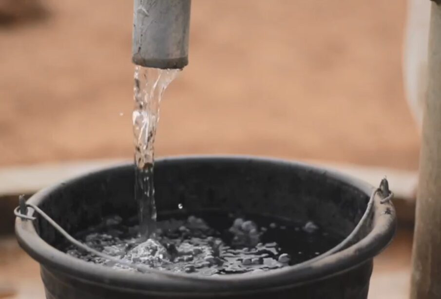 Cubeta de plástico llenándose con agua potable de una manguera.