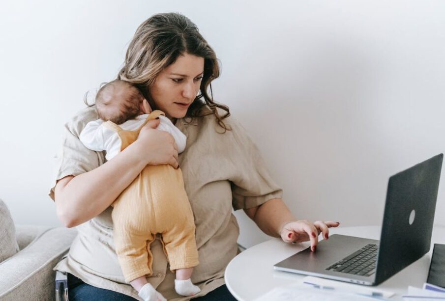 Madre trabajando con su bebé en brazos