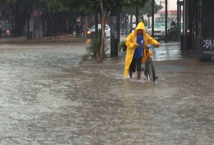 persona cruzando con su bibicleta calle inundada