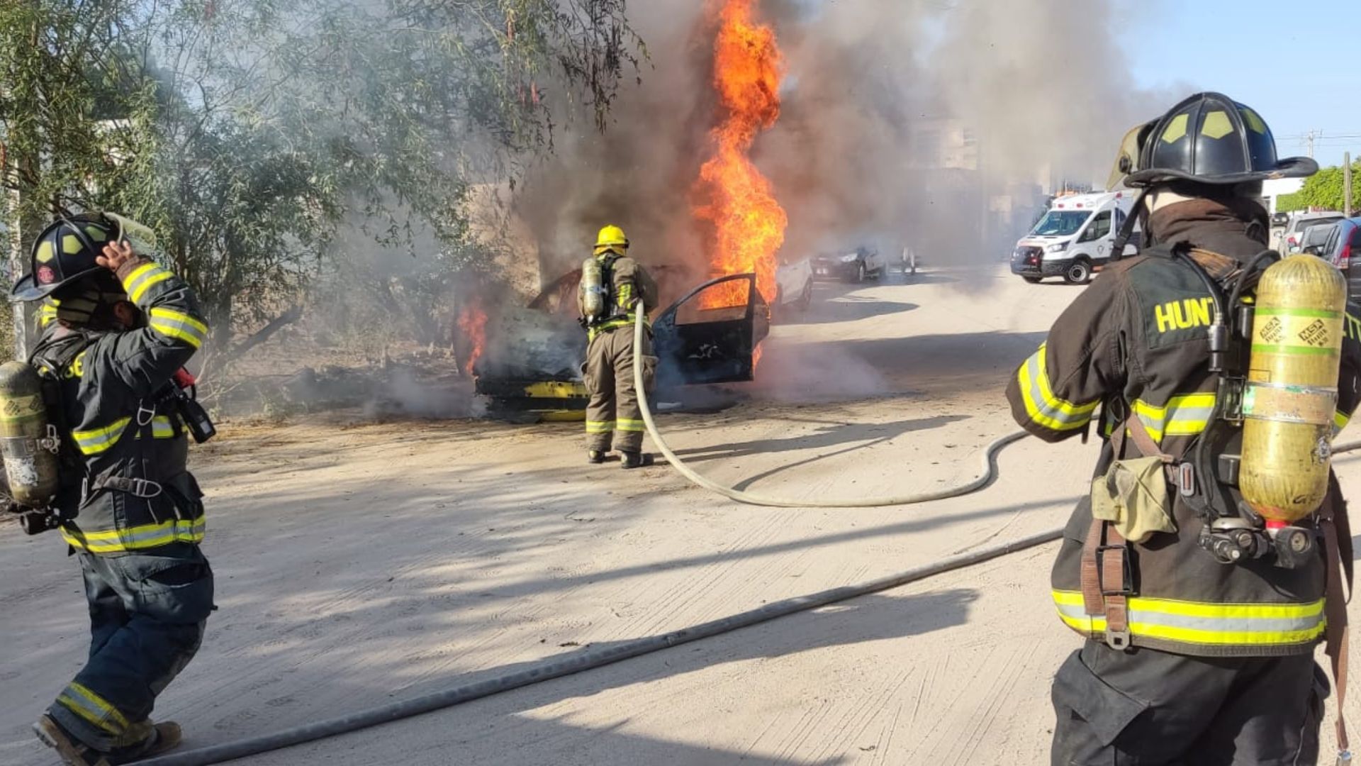 Bomberos sofocando vehículo incendiado en la colonia El Conchalito.