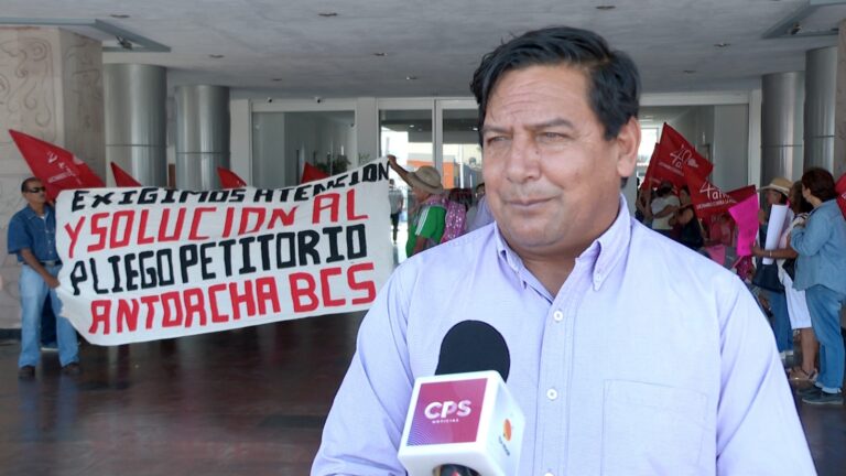 Dirigente antorchista en entrevista con manifestación de fondo