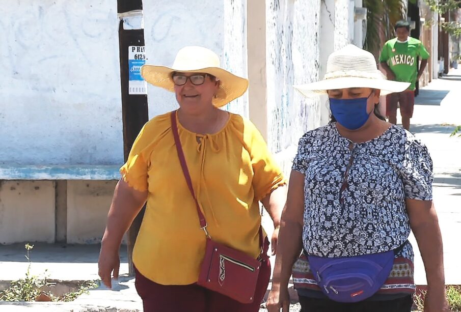 Mujeres caminando bajo el sol usando sombreros.
