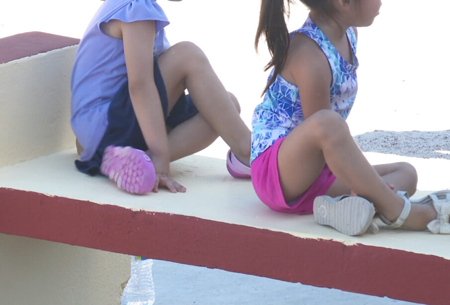 Niñas sentadas en la banca de un parque.