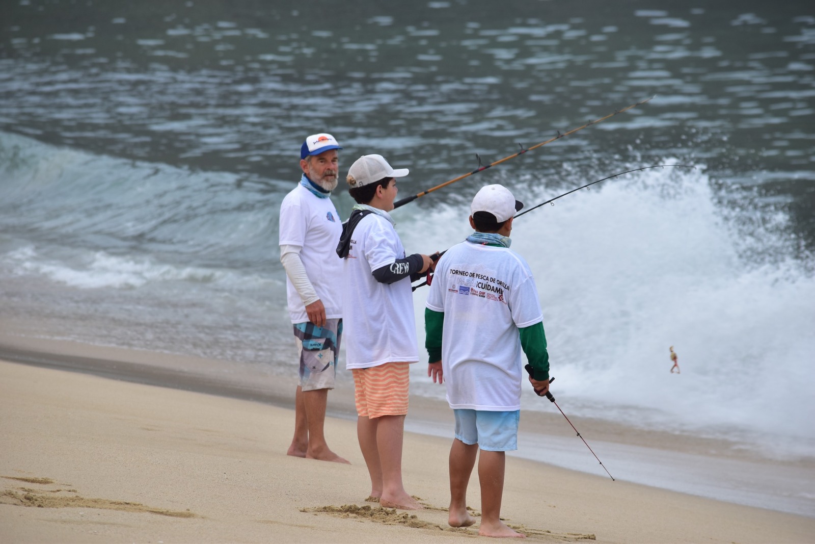 Padre e hijos pescando a la orilla de la playa en el Torneo Papá ¡Cuídame!