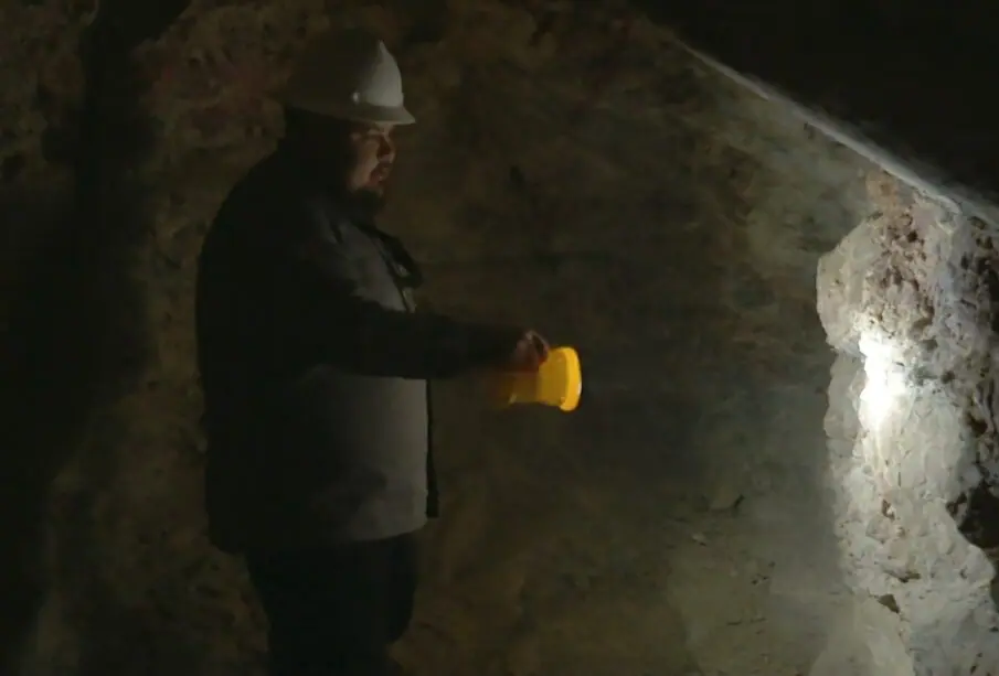 Minero alumbrando con una lámpara dentro de una cueva.