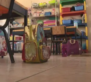 Mochila con útiles escolares en salón de clases