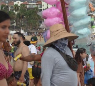 Turistas extranjeros y vendedores ambulantes en playa El Médano.