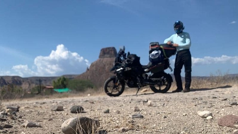 Motociclista de pie junto a su motocicleta en el desierto