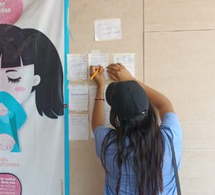 Mujer escribiendo en papeles pegados a la pared