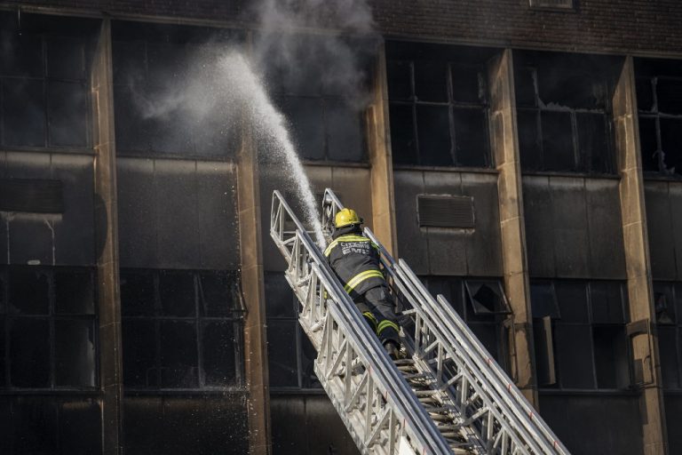 Bombero apagando fuego en edificio incendiado en Sudáfrica