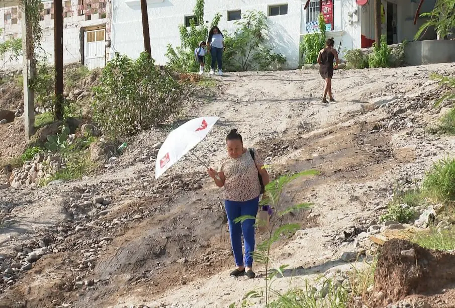 Personas caminando por calle con hoyos y zanjas