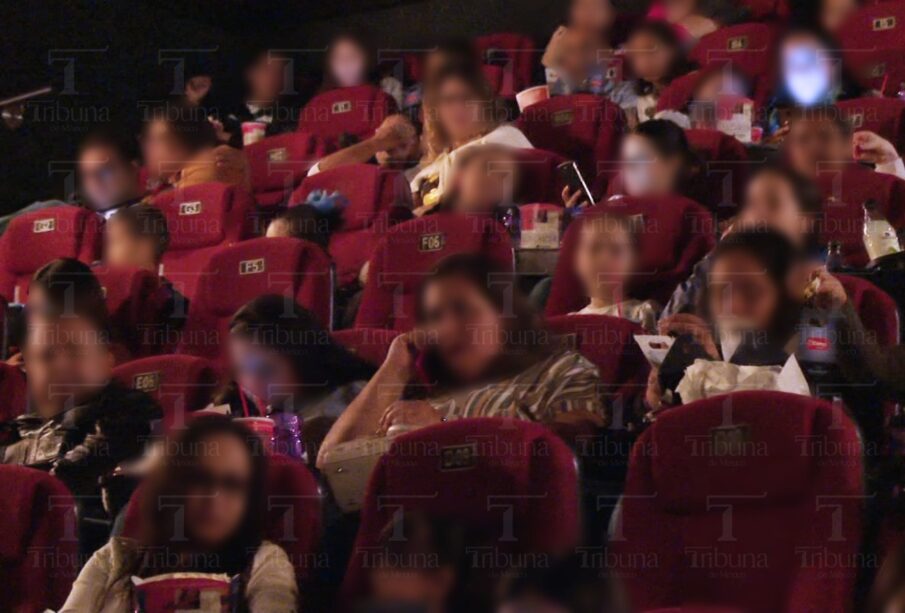 Personas sus celulares durante función en un cine.