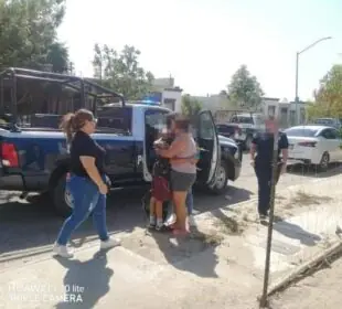 Madre abrazando a su hijo a un lado de una patrulla