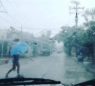 Persona cruzando calle bajo la lluvia protegiéndose con paraguas