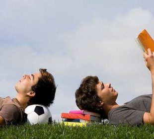 Adolescente leyendo y otro acostado sobre un balón