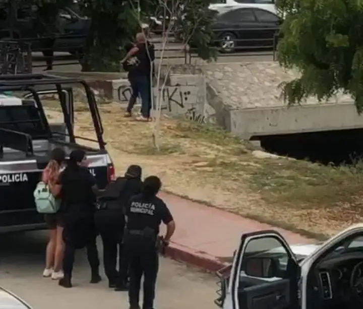 Oficiales rodeando a hombre que amenaza a mujer